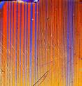 A polarized light microscopy image of structural domains in a barium-iron-arsenide crystal, a type of superconductor. Physicists at the US Department of Energy's Ames Laboratory discovered unexpected resistivity changes in crystals doped with potassium, which suggest a close relationship between magnetism and superconductivity in iron-based superconductors.