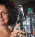 Georgia Tech associate professor Elisa Riedo poses with a glass water bottle and a plastic water bottle. While container materials don't significantly affect the rate at which water pours from bottles of this size, a new study shows that the properties of containers at the nanoscale dramatically affect the viscosity of water.
