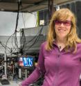 This is NIST physicist Elizabeth Donley with a compact atomic clock design that could help improve precision in ultraportable clocks. About 1 million cold rubidium atoms are held in a vacuum chamber in the lower left of the photo. On the screen is a close-up of the atom trapping region of the apparatus.
