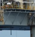 A humpback whale surfaces under the platform of an oil platform in the waters of Gabon. According to data gathered by the researchers from satellite-tagged whales, humpbacks traveling north from and remaining in the coastal waters of Gabon spent an estimated 41 percent of their time in the presence of oil and gas platforms.