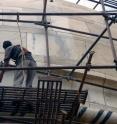 A worker cleans a portion of the Taj Mahal complex. Marble on the right shows brownish discoloration caused by particles of carbon, and dust.