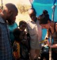 Lead author Holly Lutz showing local villagers a parasite that she found on an African black-headed oriole (Oriolus larvatus) in the camp at the base of Mount Gorongosa, in Gorongosa National Park, Mozambique.